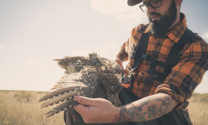 A bird hunter holds a sharp-tailed grouse
