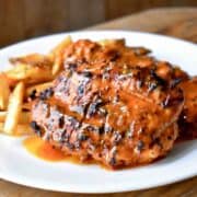 Turkey breast covered in a vibrant orange sauce, served with French fries on a white plate