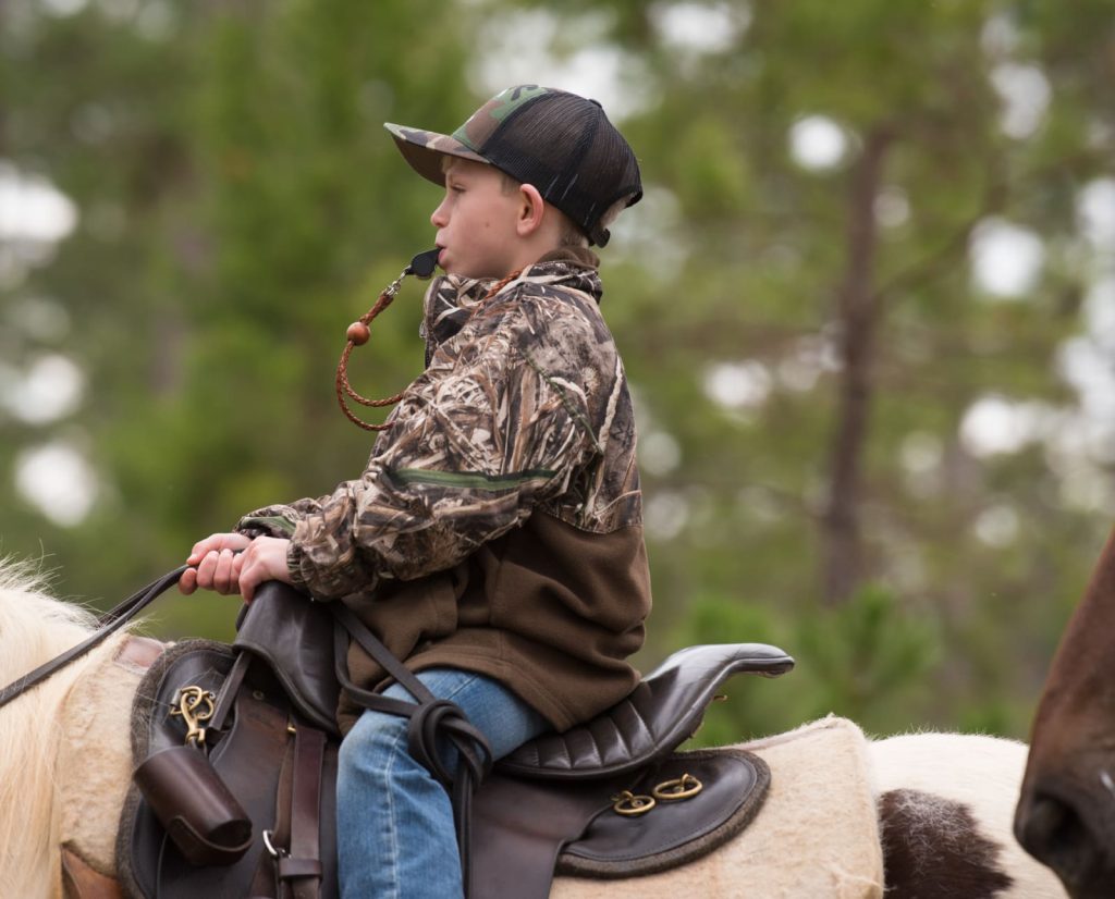 A youth field trialer riding a horse during an event. 