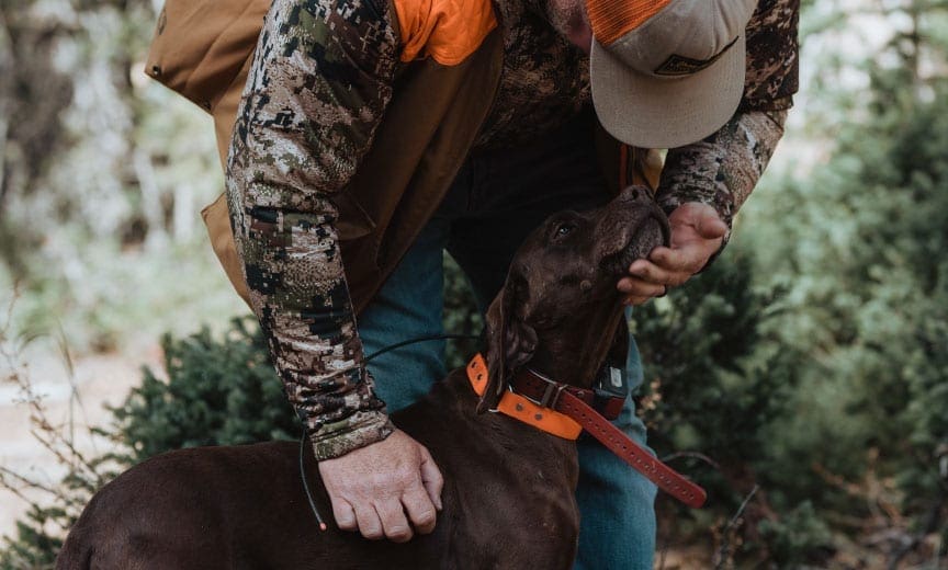 A hunter pets another hunters bird dog. 