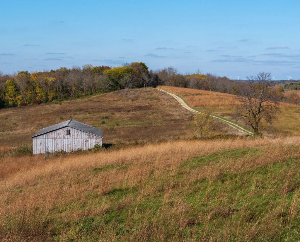 An old white barn near a road in the prairie at Horicon Marsh in Wisconsin.