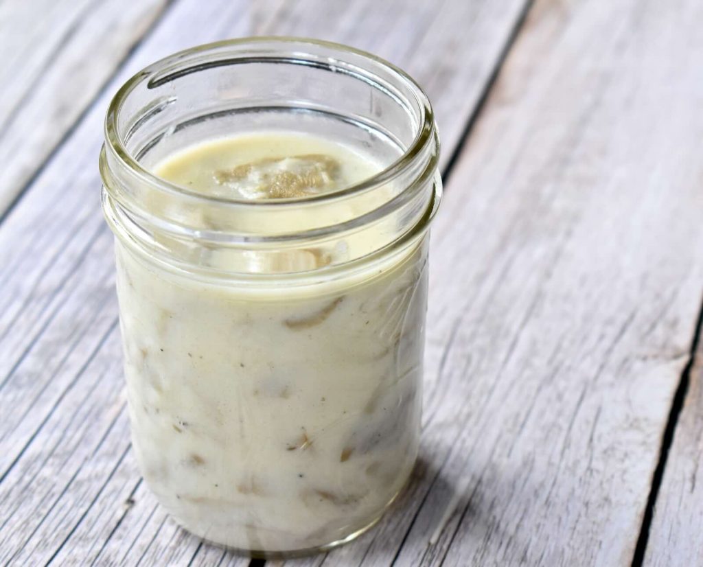 A mason jar filled with condensed cream of mushroom soup, sitting on a wooden background