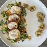 Sliced, roasted chukar served on a white plate with a purslane garnish and a mushroom sauce