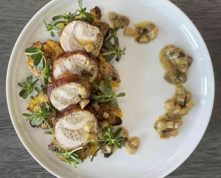 Sliced, roasted chukar served on a white plate with a purslane garnish and a mushroom sauce
