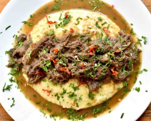 Grits served on a white plate topped with a brown gravy made from goose gizzards