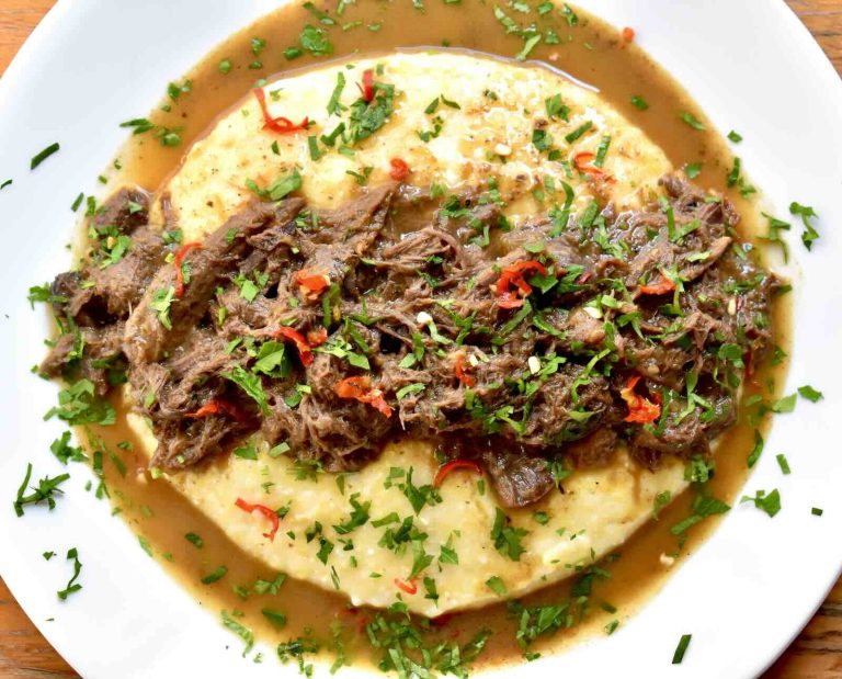 Grits served on a white plate topped with a brown gravy made from goose gizzards
