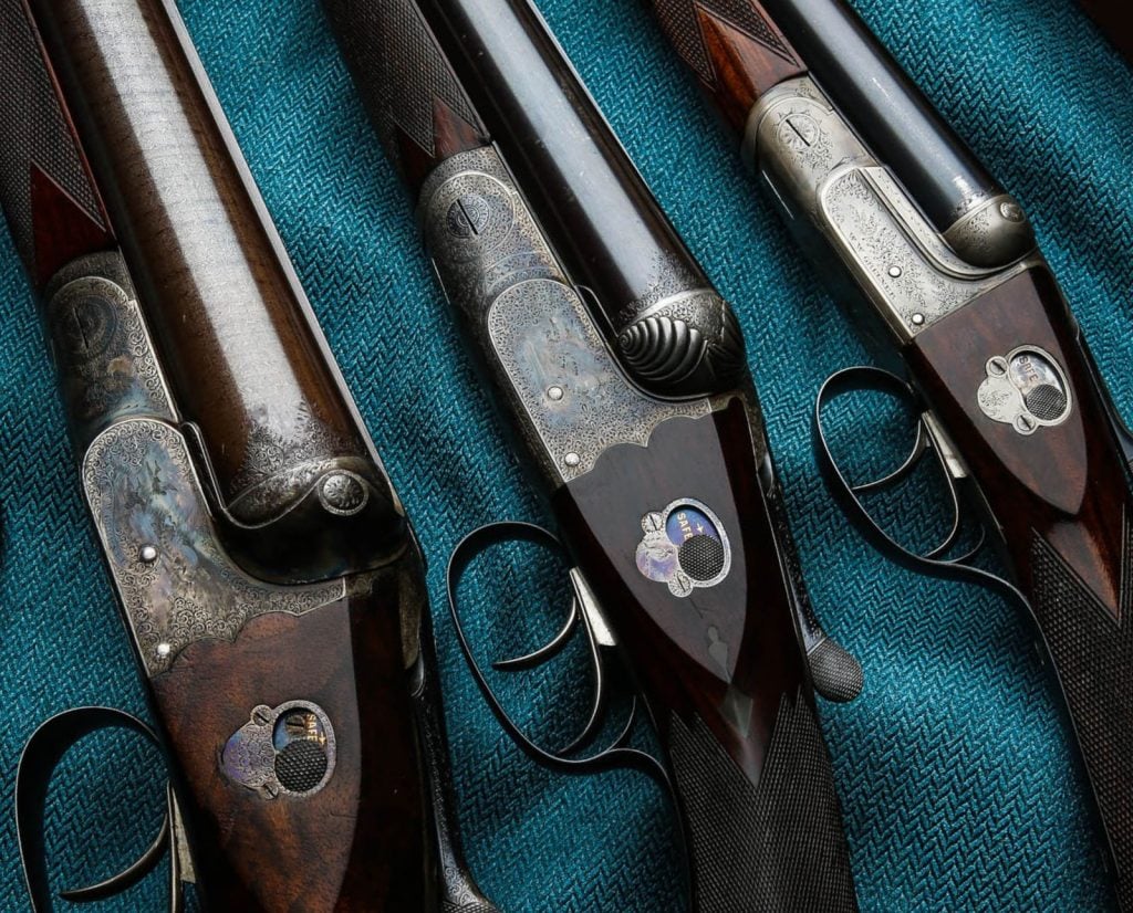 Three English W.W. Greener side-by-side shotguns lined up next to each other.
