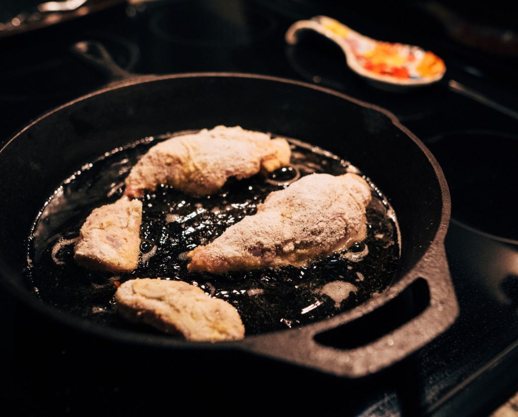 Rabbit quarters and backstrap fry in oil in a cast iron pan.