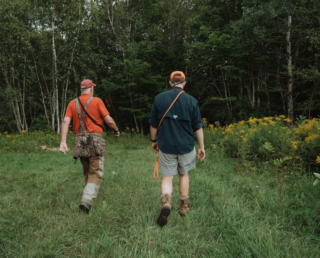 Two hunters scout a ruffed grouse hunting spot during the offseason.