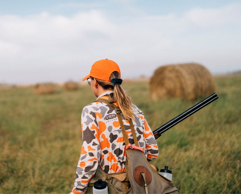 A hunter chasing pheasants on private land with hay bales.